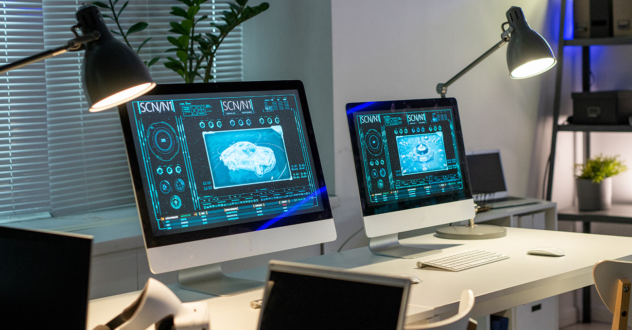 Dos monitores de computadora con interfaces futuristas, mostrando el diseño de un automóvil en 3D.